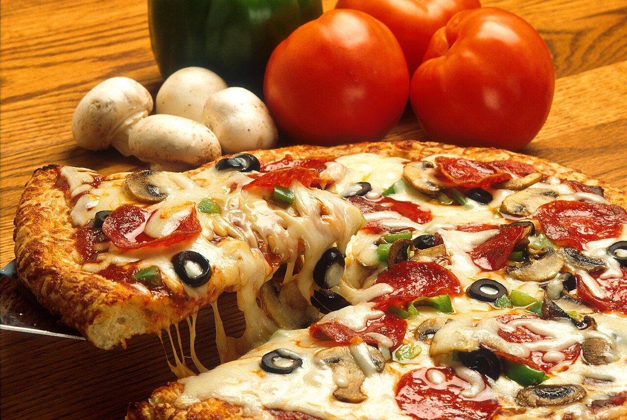 A baked pan pizza with caramelized cheese along the steel rim